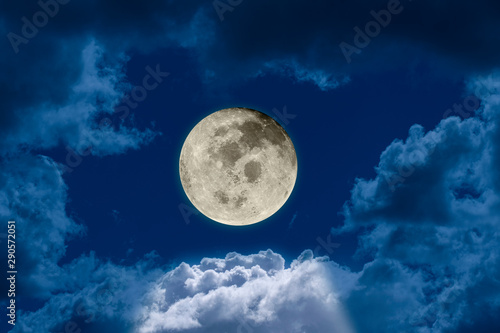 Big bright and shining full moon against a dark night sky dramatic seen through a hole in the clouds. Elements of this image furnished by NASA