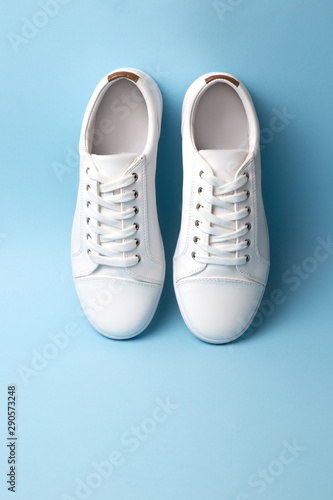 Pair of white sneakers on blue background. Fashion blog or magazine concept.