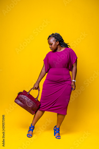 Studio shot of woman in purple dress against yellow background photo