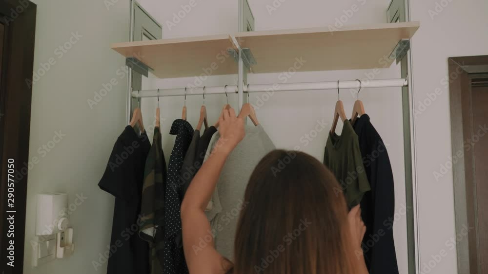 What to Wear Today? A girl looks and chooses clothes, or getting dressed in the wardrobe. Hangers with clothes. Dressing up What to Wear Today? A girl looks and chooses clothes, or getting dressed in the wardrobe. Hangers with clothes. Dressing up