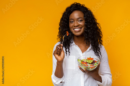 Photographie Happy african american woman eating healthy salad