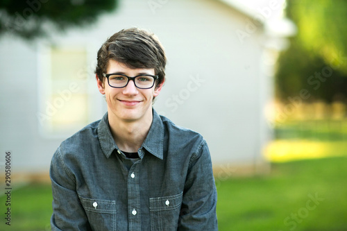 Teenage Boy with Glasses Outside on a spring day sitting outside of a house home smiling