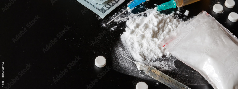 Fototapeta premium drug is a white powder, tablets, syringes sprinkled on a black table. Dangerous illegal business. Flat Lay Addiction Concept long banner