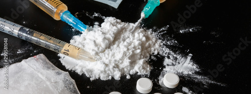drug is a white powder, tablets, syringes sprinkled on a black table. Dangerous illegal business. Flat Lay Addiction Concept long banner