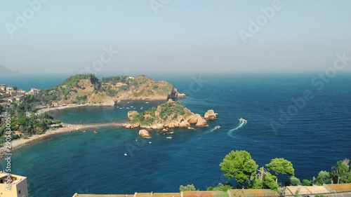 Taormina, SICILY, Italy - August 2019: Paradise place. Beach - the ocean is surrounded by mountains and cliffs. Many trees. Tracers from yachts on the water. Aerial drone shot.