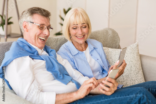 Happy mature couple watching funny videos on phone