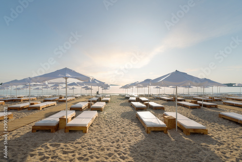 Beautiful beach. Sun umbrellas on blue sky background on seashore. Chairs on the sandy beach near the sea. Summer holiday and vacation concept for tourism. Inspirational tropical landscape.