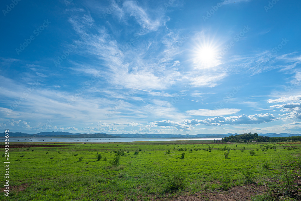 large green field beside the dam in blue sky