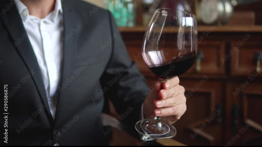 Man wearing black suit with a glass of red wine Man wearing black suit with a glass of red wine