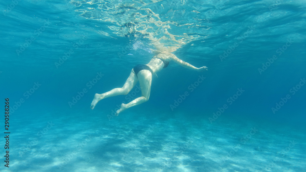 Underwater photo of woman swimming in tropical exotic bay with crystal clear sea