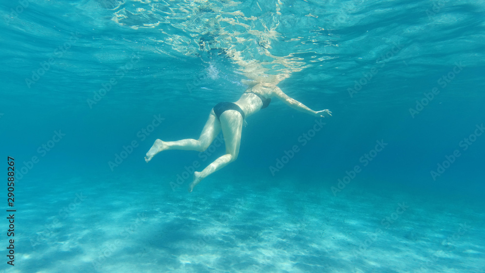 Underwater photo of woman swimming in tropical exotic bay with crystal clear sea