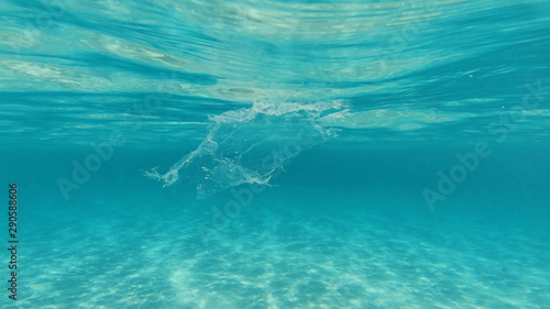 Underwater photo of plastic bag floating in tropical exotic turquoise sandy beach