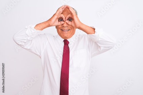 Senior grey-haired businessman wearing elegant tie over isolated white background doing ok gesture like binoculars sticking tongue out, eyes looking through fingers. Crazy expression.