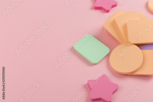 A lot of sponge, a beautiful blender for applying foundation or powder. Flat lay on a pink background, copy space.