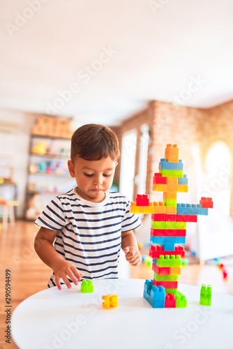 Beautiful toddler boy playing with construction blocks at kindergarten
