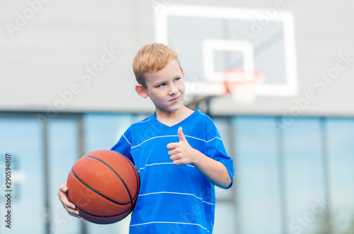 Adorable child playing the basketball in the basket field