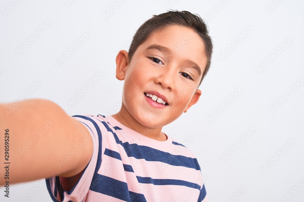 Beautiful kid boy wearing casual striped t-shirt make selfie over isolated white background with a happy face standing and smiling with a confident smile showing teeth Beautiful kid boy wearing casual striped t-shirt make selfie over isolated white background with a happy face standing and smiling with a confident smile showing teeth