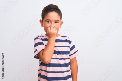 Beautiful kid boy wearing casual striped t-shirt standing over isolated white background looking stressed and nervous with hands on mouth biting nails. Anxiety problem.