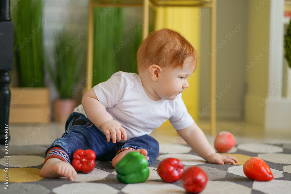 chubby fatty baby child with plus size body and red hair plays with vegetables and like his diet on room background chubby fatty baby child with plus size body and red hair plays with vegetables and like his diet on room background