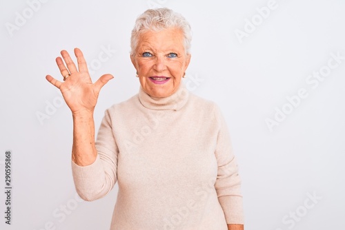 Senior grey-haired woman wearing turtleneck sweater standing over isolated white background showing and pointing up with fingers number five while smiling confident and happy.