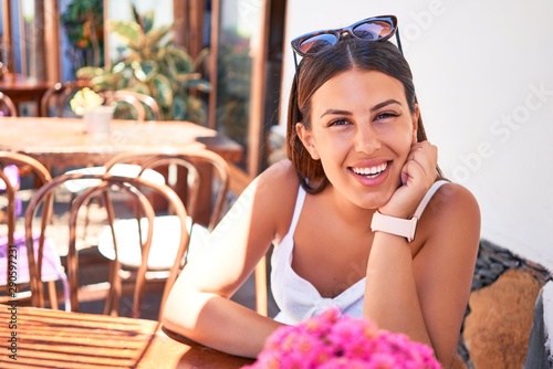 Young beautiful woman sitting at restaurant enjoying summer vacation