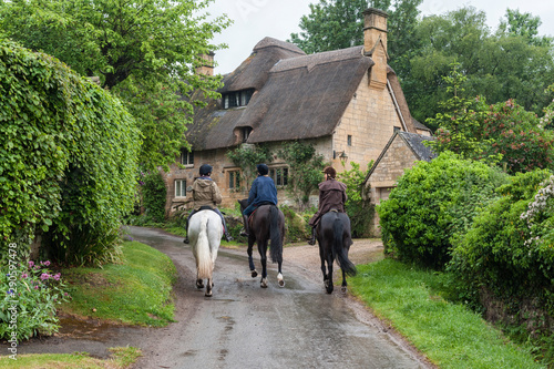 STANTON, ENGLAND - MAY, 26 2018:  Unidentifed people and horses near cottages in the village of Stanton, Cotswolds district of Gloucestershire.   photo