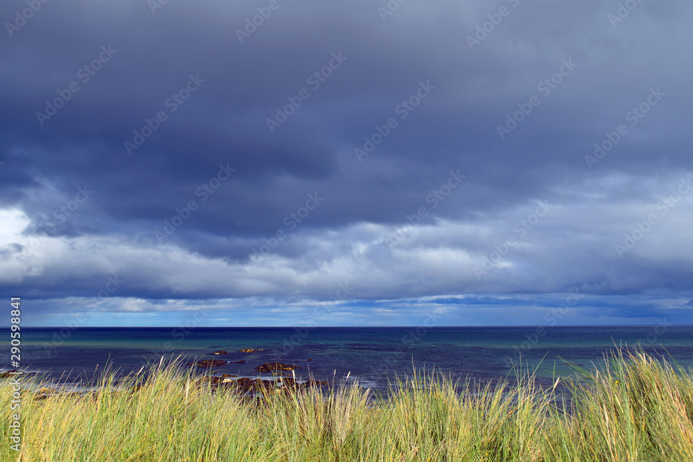 Storm clouds above coast showing grass and sea beyond, taken near Wick in Scottish Highlands (part of North Coast 500 route), lots of space for text.