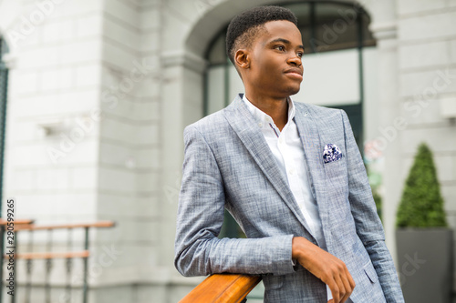handsome young african man in suit near building