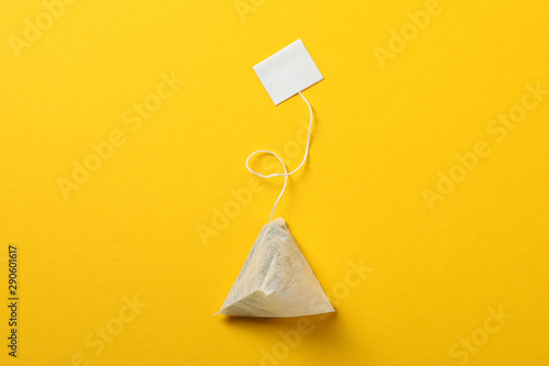 Tea bag with label on yellow background, space for text photo