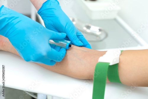 a nurse in the clinic inserts a catheter into a vein for blood testing for a young girl