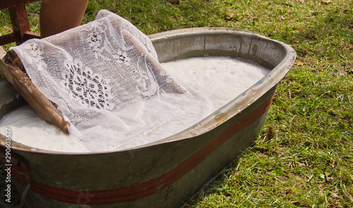 An old fashioned washing trougth filled with water, a vintage washboard and soap that wash the laundry photo