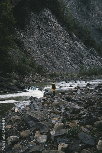 Traveler in the yellow jacket near mountain and river Carpathians Ukraine