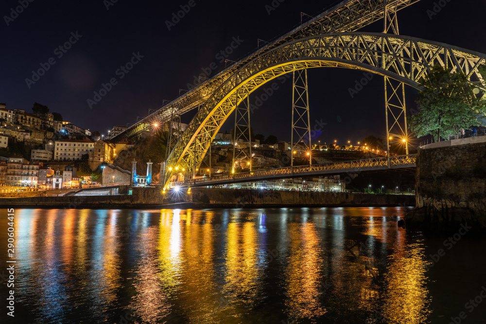 Night illuminated metal arch bridge of Ponte Luis I from the banks of the river Douro