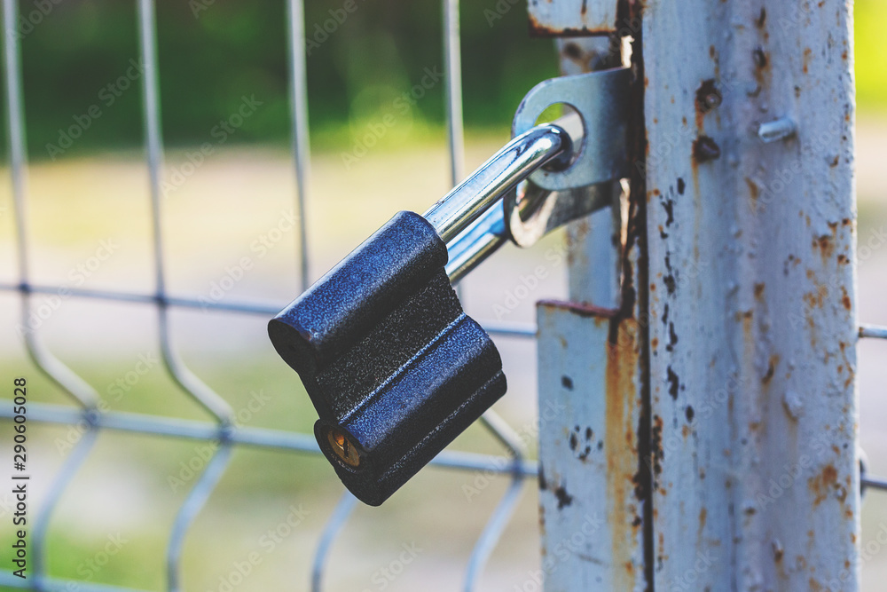 black padlock closes a metal mesh gate black padlock closes a metal mesh gate