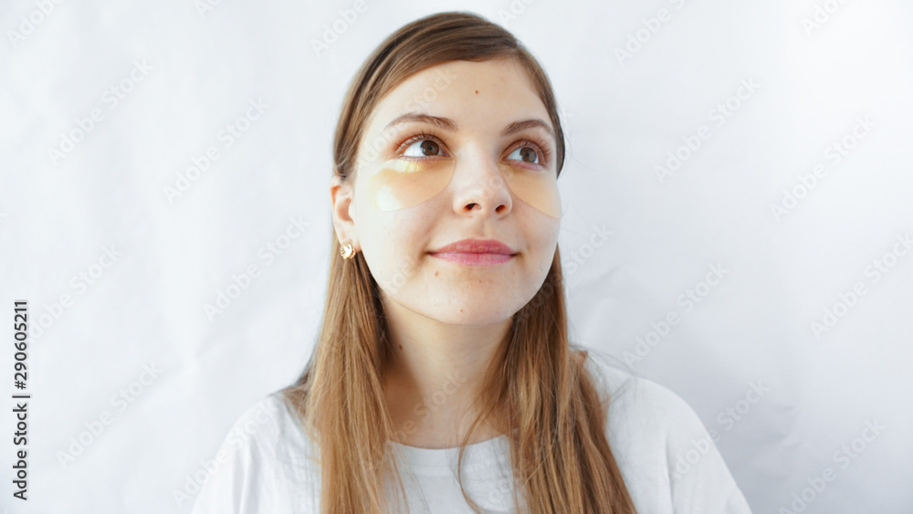 Close up portrait of pretty, charming, attractive girl using, having, applying patches under close eyes, fight with dark circles, standing over white background, wellbeing concept Close up portrait of pretty, charming, attractive girl using, having, applying patches under close eyes, fight with dark circles, standing over white background, wellbeing concept