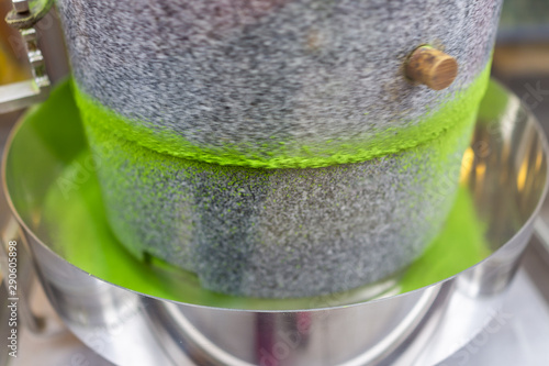 Matcha green tea grinding stone machine in motion with vibrant colorful powder in factory or tea shop