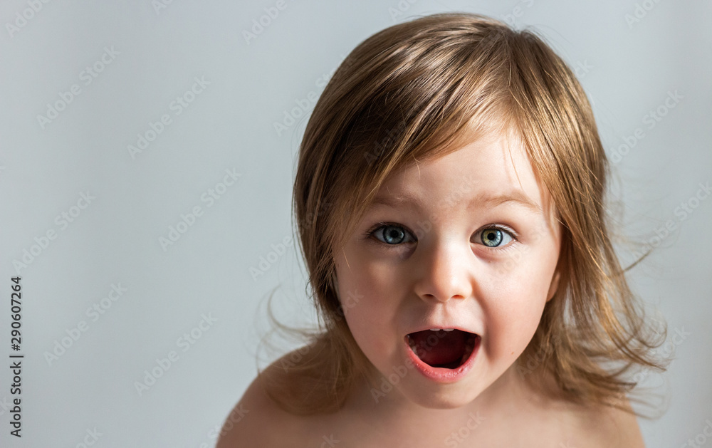 Happy excited toddler child girl closeup portrait isolated on grey background Happy excited toddler child girl closeup portrait isolated on grey background