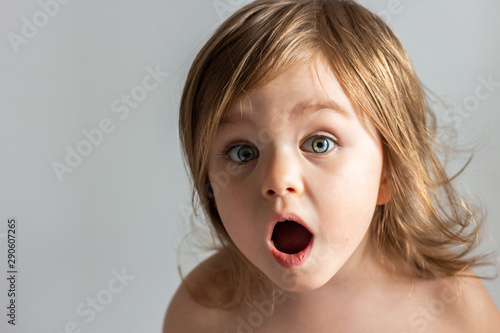 Excited shocked toddler child girl with her mouth open closeup portrait isolated on grey background