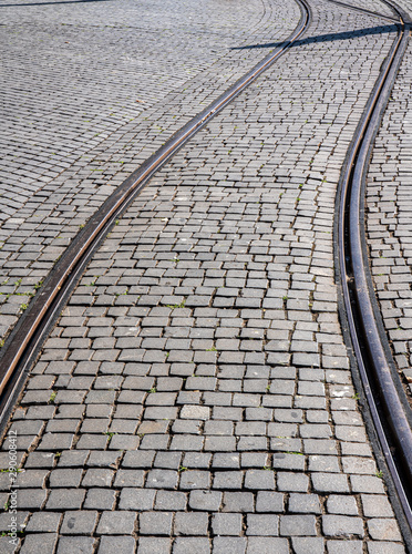 Curve of steel rails from tramcar track set into stone cobble pattern in Porto