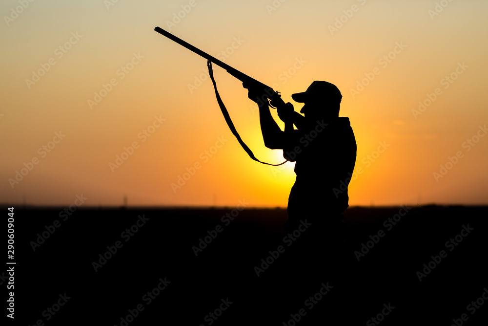 Hunting period, autumn season open. A hunter with a gun in his hands in hunting clothes in the autumn forest in search of a trophy. A man stands with weapons and hunting dogs tracking down the game. Hunting period, autumn season open. A hunter with a gun in his hands in hunting clothes in the autumn forest in search of a trophy. A man stands with weapons and hunting dogs tracking down the game.