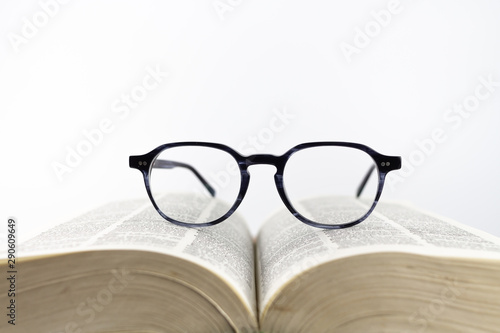 Close-up of a reading glasses on an open book on a white background