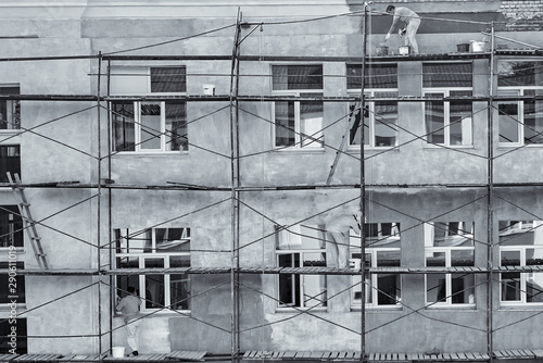 Workers paint and plaster the facade of the house, black and white photo.
