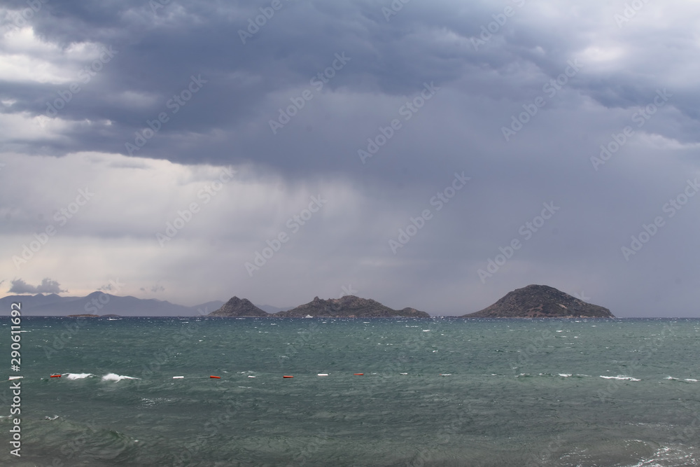 Heavy, storm clouds over the ocean, herald the arrival of a storm. Beautifully illuminated dark clouds and reflections in the ocean water Heavy, storm clouds over the ocean, herald the arrival of a storm. Beautifully illuminated dark clouds and reflections in the ocean water