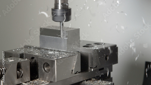 CLOSE UP: Drill cutting and shaving a piece of metal into an unfinished product. photo