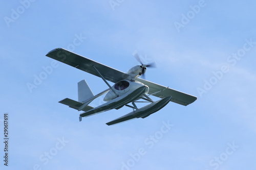 Floatplane (seaplane or hydroplane) flying in blue sky closeup. Cabin, wings propeller, engine, tail of plane are visible in details.