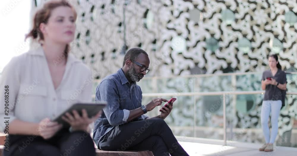 Businessman using smartphone and wearing smartwatch on office rooftop terrace Businessman using smartphone and wearing smartwatch on office rooftop terrace