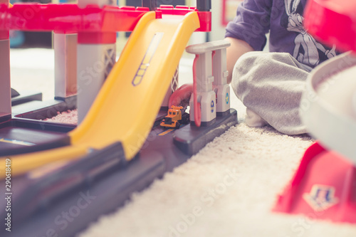 Toddler playing on the floor with his car in a colorful toy parking