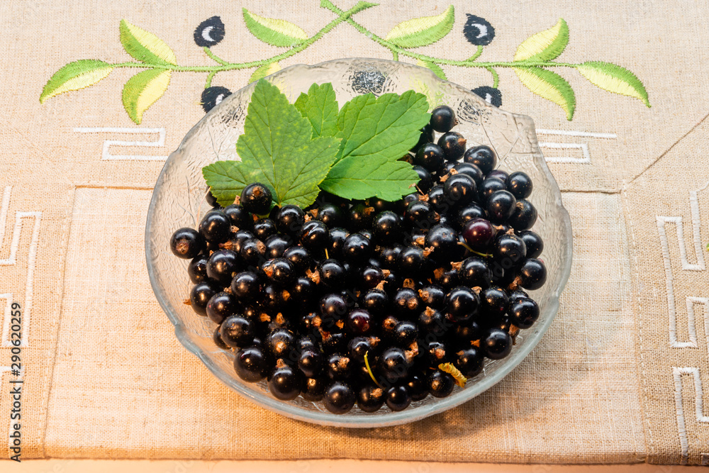Blackcurrant berries with leaves, blackcurrant in a bowl Blackcurrant berries with leaves, blackcurrant in a bowl