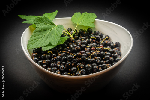 Blackcurrant berries with leaves, blackcurrant in a bowl