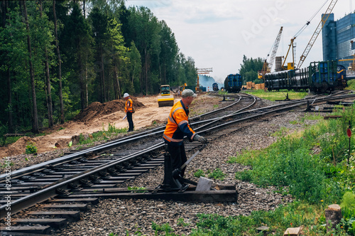 Foto Workers on railway and freight train transporting large diameter pipes